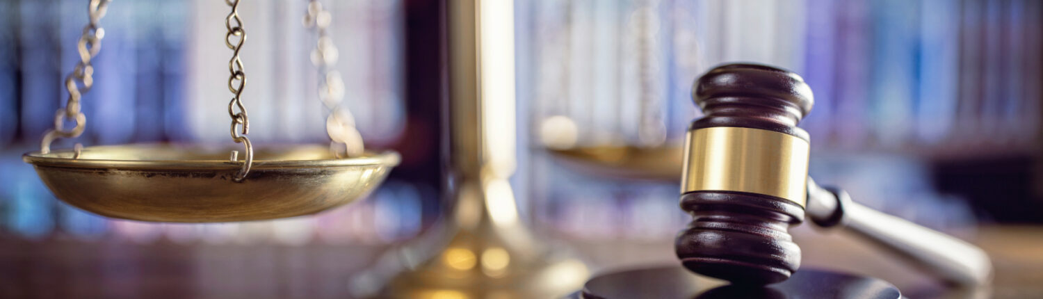 Richterhammer, Waage der Gerechtigkeit und Gesetzbücher im Gerichtssaal